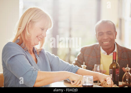 Mature woman cutting bread, senior man smiling Stock Photo