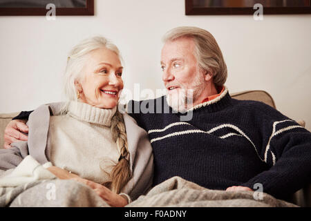Senior couple sitting on sofa, smiling Stock Photo