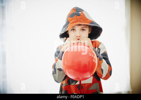 Young boy blowing red balloon Stock Photo