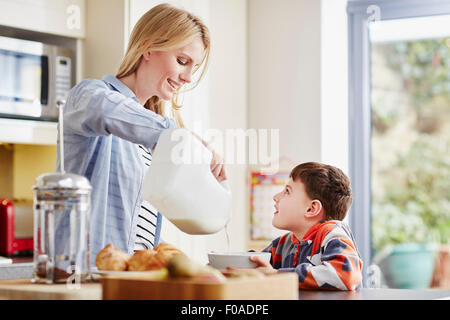 Mother pouring milk into son's breakfast bowl Stock Photo
