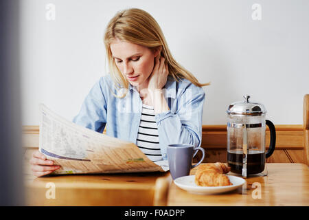 Mid adult woman reading newspaper Stock Photo