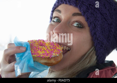 Young woman biting doughnut