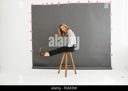 Woman on stool in front of photographers backdrop Stock Photo