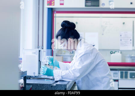 Young female scientist in lab pipetting sample Stock Photo