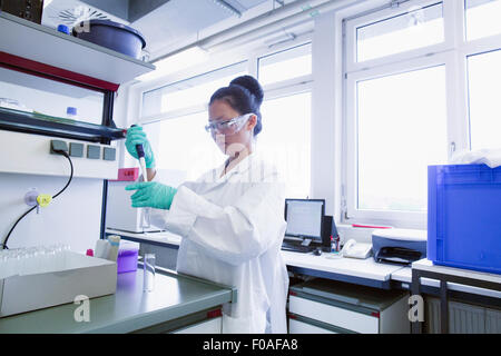 Female scientist pipetting sample into volumetric flask Stock Photo