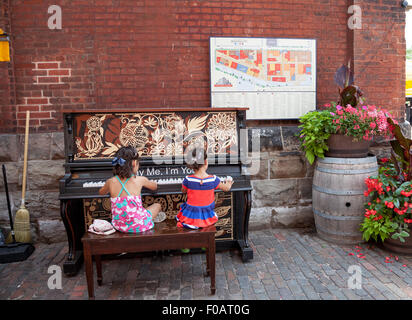 two young girls 4-6 years of age are playing the piano outdoors at the Distillery District in Toronto;Ontario;Canada Stock Photo