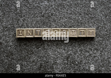 integrity word made from metallic blocks on blackboard surface Stock Photo