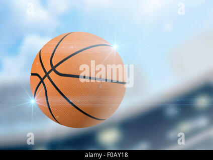 A regular basketball flying through the air on a stadium background during the daytime Stock Photo