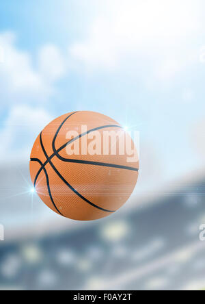 A regular basketball flying through the air on a stadium background during the daytime Stock Photo