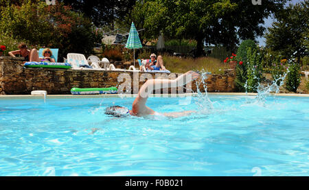 Young woman on holiday swimming front crawl in a pool by a gite at Frayssinet-le-Gelat in the Lot Region Department of France Stock Photo