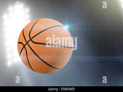 A regular basketball flying through the air on an a outdoor stadium background during the night Stock Photo