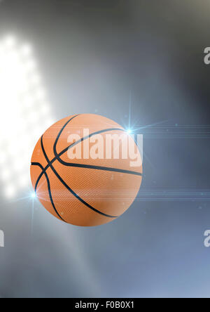 A regular basketball flying through the air on an a outdoor stadium background during the night Stock Photo