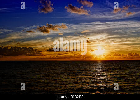 Sunbeams emanating from behind low altitude clouds at sunrise Stock Photo