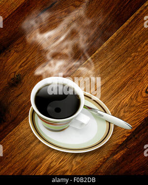 Cup of hot coffee with Yin Yang steam on wooden background. Stock Photo