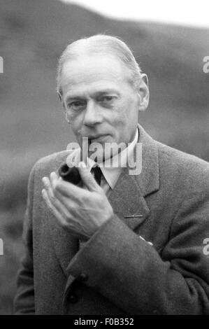 A mature man wearing a coat and smoking a pipe Stock Photo