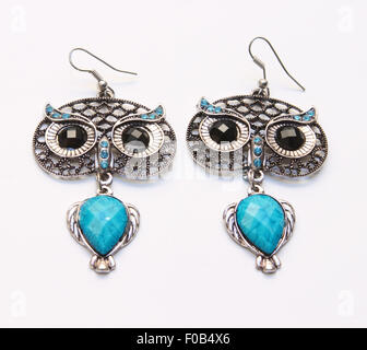 metal earrings in owl shape with blue stone on white background Stock Photo