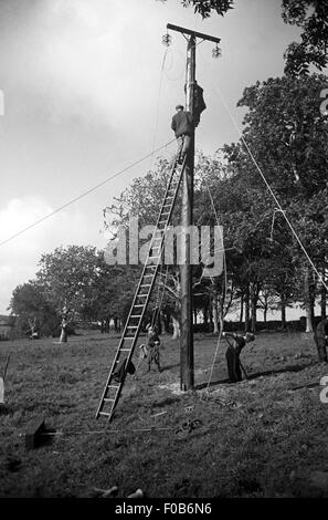 Two men working on the power lines above. Stock Photo