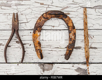 Horseshoe and various tools on an old white painted surface Stock Photo