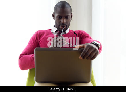 Portrait of handsome young man working with his laptop at home. Stock Photo