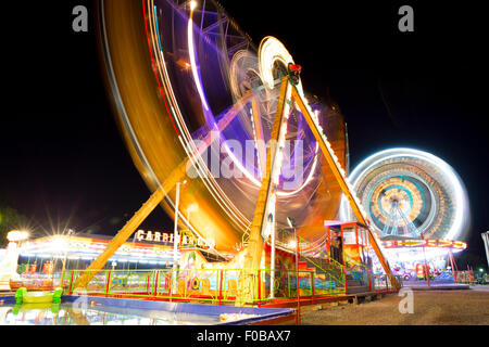 Colorful carnival Ferris wheel and gondola spinning in motion blurred at night in an amusement park Stock Photo