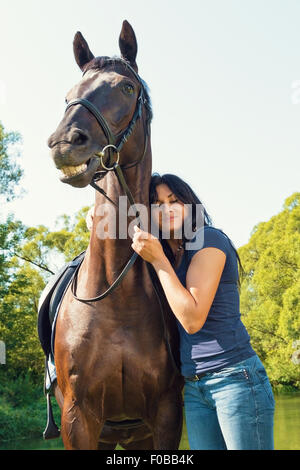 Portrait of happy woman and the horse in the summer outdoors. Stock Photo