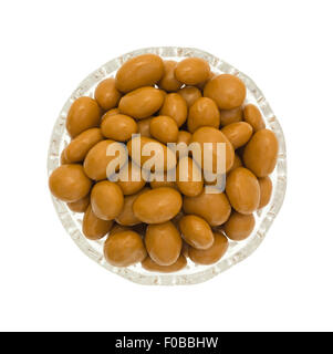 Top view of a small glass bowl filled with caramel coated raisins on a white background. Stock Photo