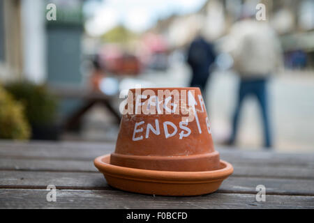 Upturned flower pot used as Fag ends bin pot ashtray on bench on High Street Burford Cotswolds Oxfordshire England Uk Europe Stock Photo