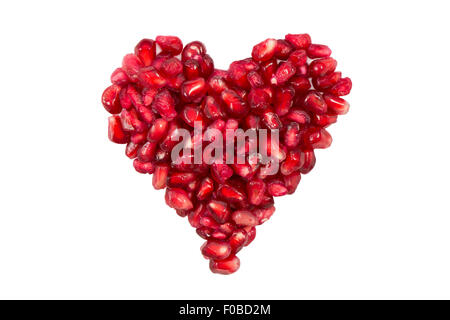 Red heart shape made of pomegranate seeds isolated on white background. Stock Photo