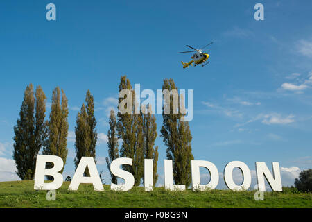 The now iconic Basildon sign at the entrance to the Essex town with the Herts and Essex Air Ambulance landing next to it. Stock Photo
