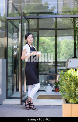 Shopkeeper standing in doorway of coffee shop Stock Photo
