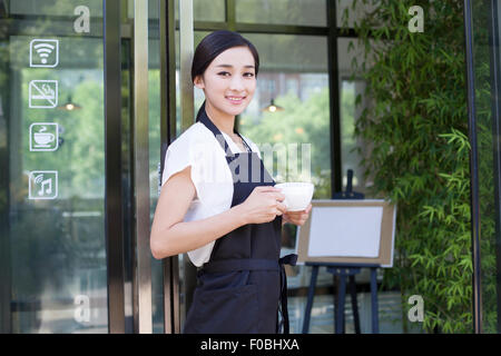 Shopkeeper standing in doorway of coffee shop Stock Photo