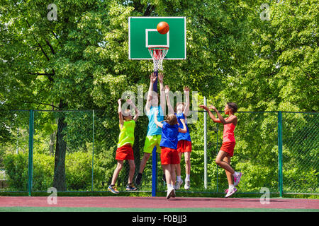 Happy teenagers playing basketball on playground Stock Photo