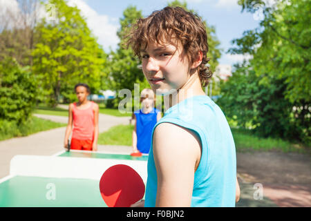 Boy with racket turned and playing table tennis Stock Photo