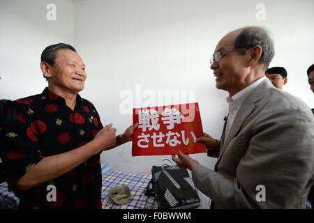 Mudanjiang City, China. 11th Aug, 2015. 73-year-old Japanese Yohachi Nakajima (R), a 'war orphan' left in China after WWII, presents an anti-war slogan to his Chinese teacher in Mudanjiang City, northeast China's Heilongjiang Province, Aug. 11, 2015. Nakajima went to northeast China's Heilongjiang province in 1942 with his family as members of 'the Japanese settlers group' when he was only a one-year-old baby. But in 1945, when the militaristic Japan surrendered at the end of World War II, he was left in China solely. Credit:  Xinhua/Alamy Live News Stock Photo