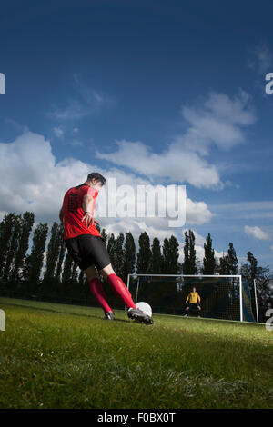 Full length of soccer player kicking ball at goal Stock Photo