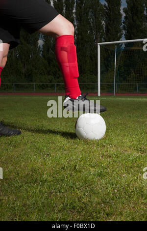 Low section of soccer player with foot on ball in front of goal post Stock Photo
