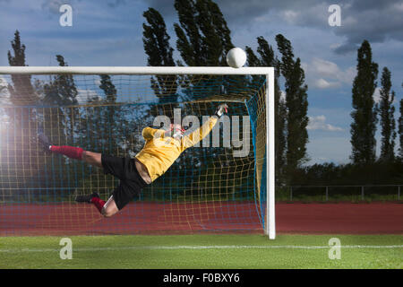 Full length of soccer goalkeeper diving to block ball Stock Photo