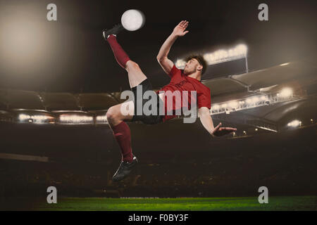 Full length of soccer player kicking ball on field Stock Photo