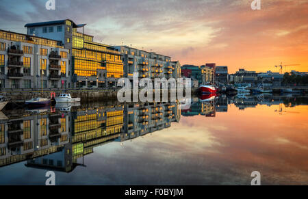 morning view on row of buildings and fishing boats in Galway Dock with sky reflected in the water, HDR image Stock Photo