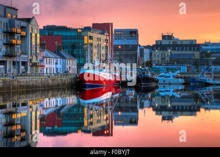 morning view on row of buildings and fishing boats in Galway Dock with sky reflected in the water, HDR image Stock Photo