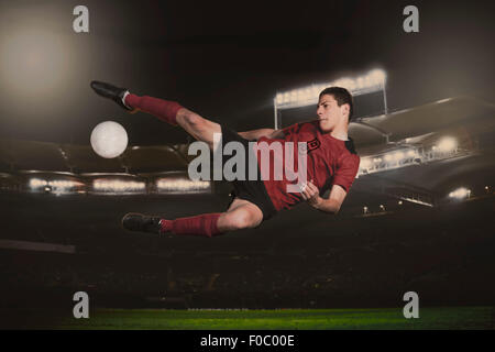 Full length of soccer player kicking ball during match Stock Photo