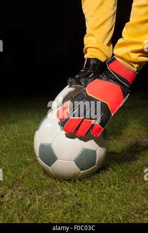 Cropped image of young male goalie placing soccer ball on field Stock Photo