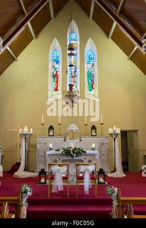 Wedding flowers with candles set up on the altar in catholic church. Stock Photo