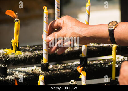 Male hand lights a candle in a Buddhist monastery in Bangkok Stock Photo