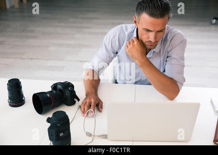 Portrait of a photographer using laptop at his workplace Stock Photo