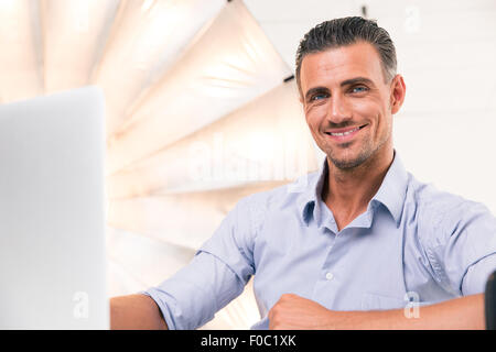 Happy confident man using laptop and looking at camera in studio Stock Photo