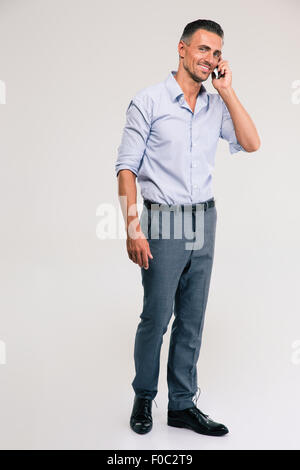 Full length portrait of a smiling businessman talking on the phone isolated on a white Stock Photo