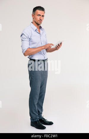 Full length portrait of a handsome man using tablet computer isolated on a white background. Looking at camera Stock Photo