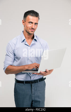 Portrait of a happy businessman using laptop and looking at camera Stock Photo