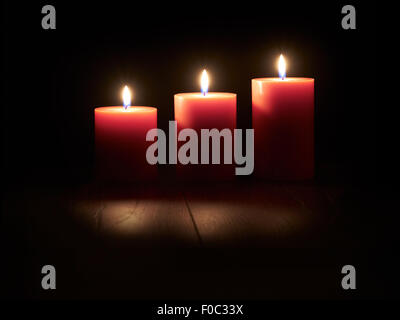 Lit red candles on a dark wooden floor with black background Stock ...